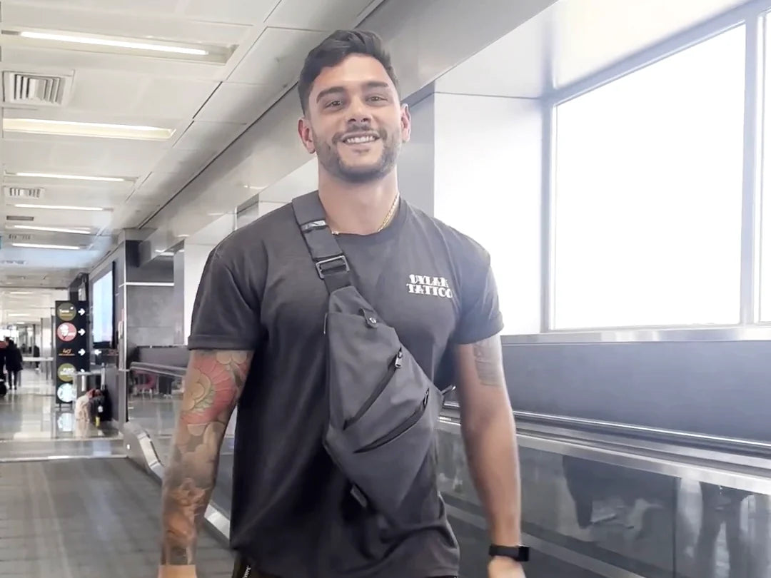 A traveler walking through the airport with the gray FlyHugz Anti-Theft Bag across his chest