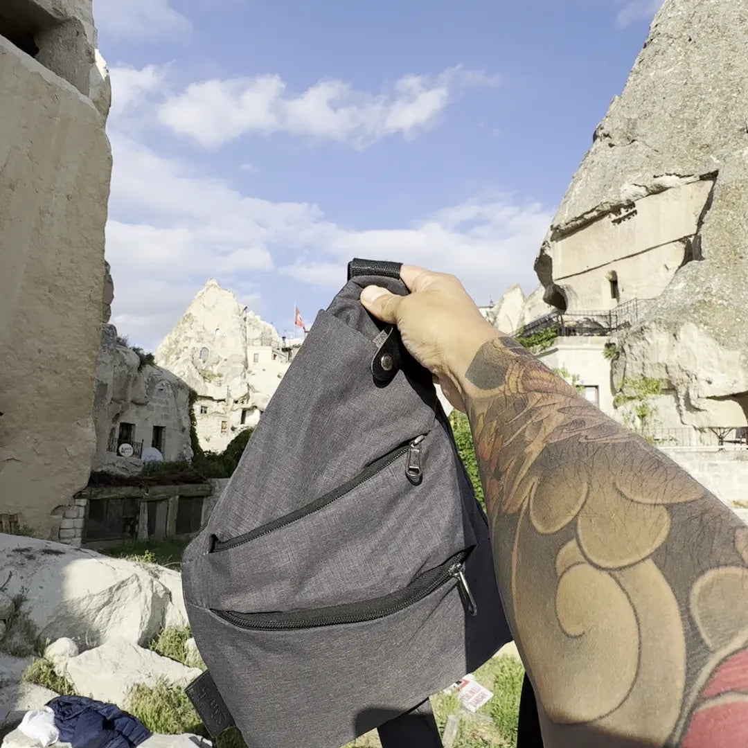 The gray FlyHugz Anti-Theft Bag held up over Cappadocia